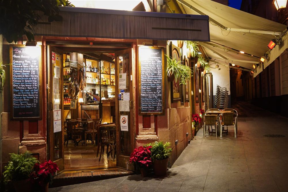 A small café entrance lit at night, with chalkboard menus either side of the door