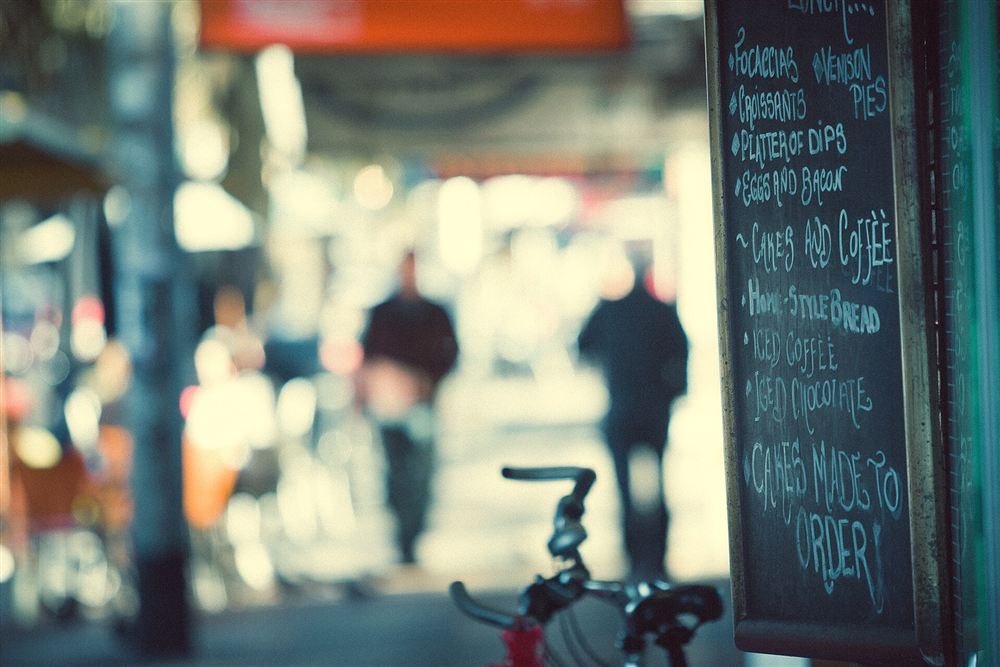 A handwritten chalkboard menu beside a blurred street