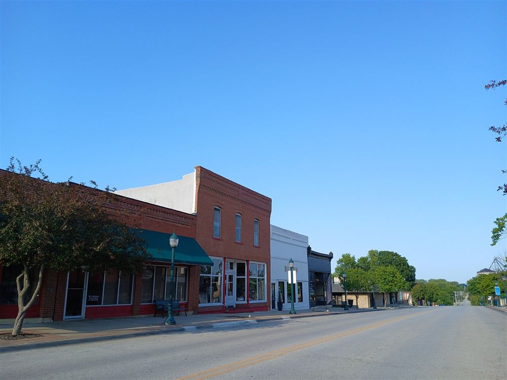 A quiet downtown street of brick storefronts on a sunny morning