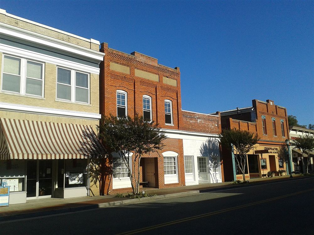 A row of brick storefronts with a striped awning under a clear blue sky